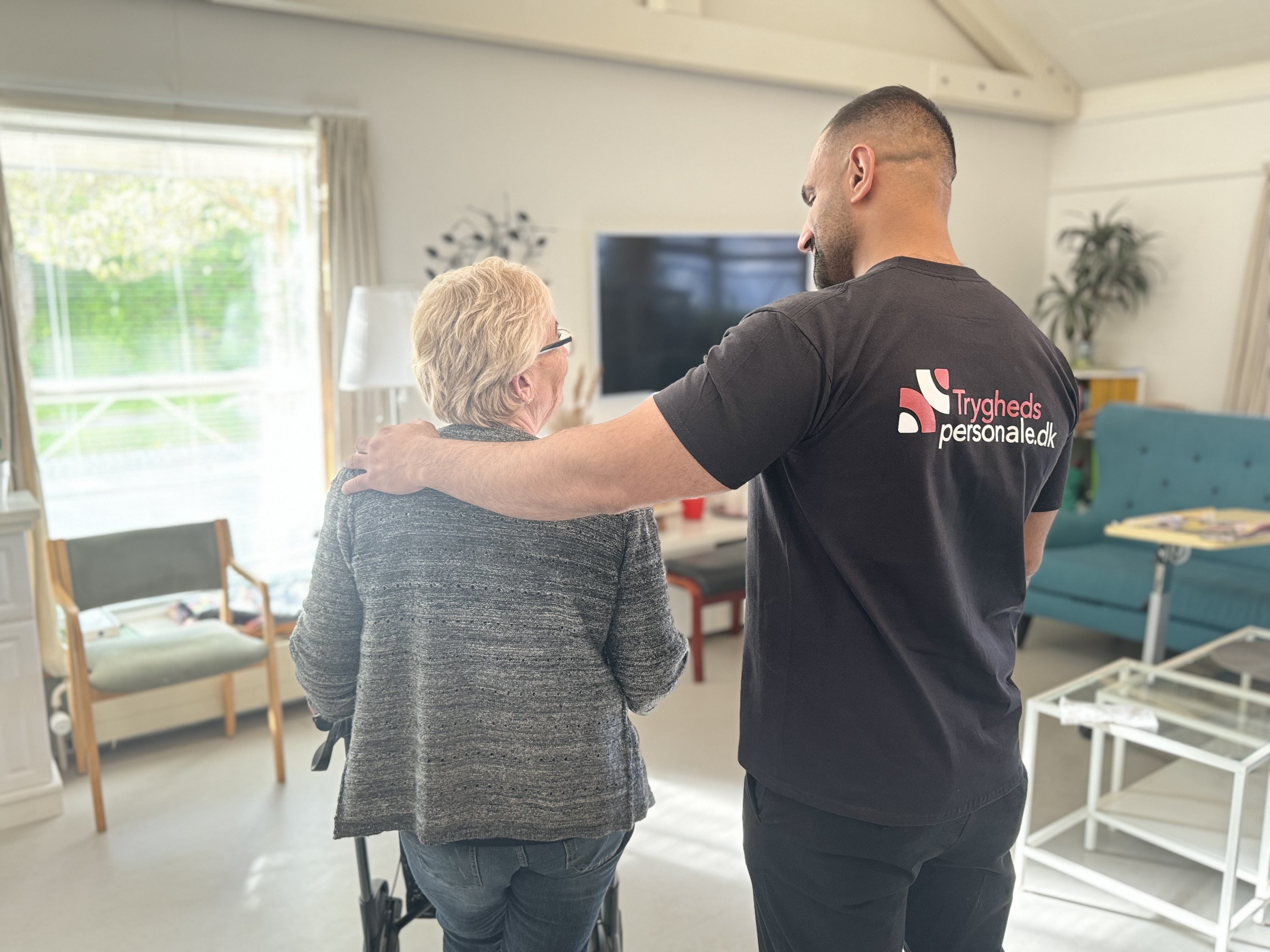 Tryghedspersonale medarbejder støtter ældre borger med demens - skaber tryghed gennem nærvær og professionel omsorg på plejehjem med udadreagerende beboere